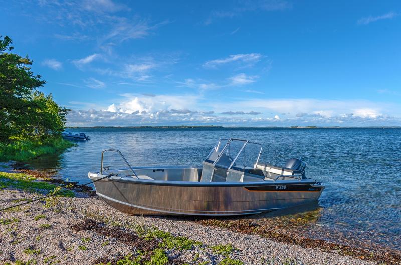 Buster M2 kaksipulpettinen mökkivene vedettynä hiekkarannalle